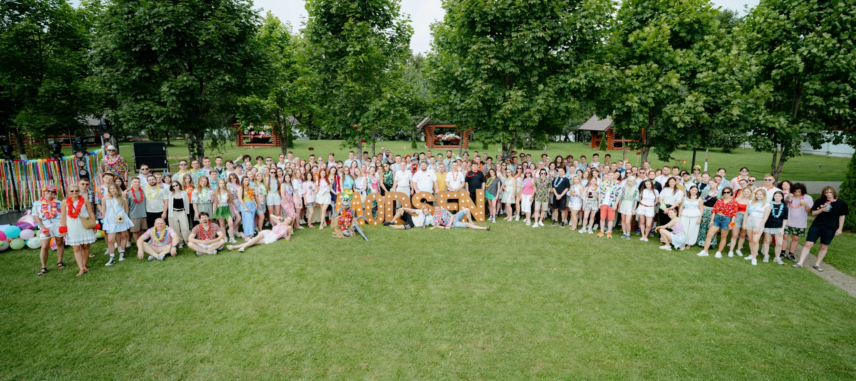 Modsen Summer Corporate Event Modsen team posing together in front of MODSEN letters at a summer corporate event